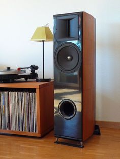 a pair of speakers sitting on top of a wooden floor next to a record player