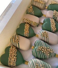 green and white heart shaped cookies with gold decorations in a box on top of a table