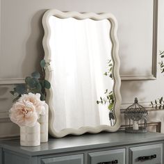 a mirror sitting on top of a dresser next to a vase