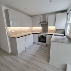 an empty kitchen with white cabinets and gray counter tops