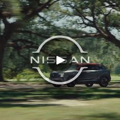 a car driving down a road with trees in the background and nissan logo on it