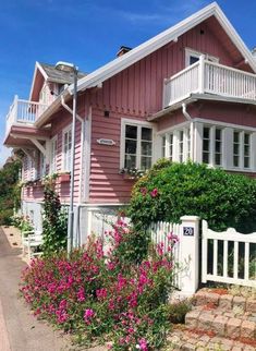 pink house with white picket fence and flowers in front