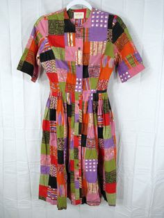 a multicolored shirt dress hanging on a hanger against a white backdrop with an image of squares and rectangles