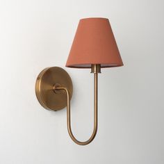 a wall light with a pink shade on it's side and a white wall in the background