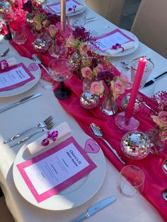 the table is set with pink and silver place settings, plates, utensils, and napkins