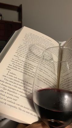 a glass of wine sitting on top of an open book