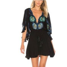 Take A Walk On The Wild Side With The Free People Cora Black Embroidered Dress! Intricate Navy Blue, Teal, And Olive Green Embroidery Decorates This Flirty Woven Dress With A Scalloped, Plunging Neckline And Wide, Fluttering Sleeves With Side Slits. Elastic Waistband, And An Tasseled, Wrap Belt Tops A Leg-Baring Mini Skirt. Skirt Is Lined. 100% Viscose. Machine Wash Cold. Black Embellished Beach Dress, Black V-neck Boho Dress For Festival, Black Long Sleeve Embroidered Beach Dress, Black Embroidered Beach Dress For Spring, Spring Beach Black Embroidered Dress, Spring Beach Embroidered Black Dress, Black Bohemian Embroidered Mini Dress, Casual Embellished Beach Dresses, Black Embroidered V-neck Mini Dress