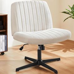 a white office chair sitting on top of a wooden floor next to a book shelf