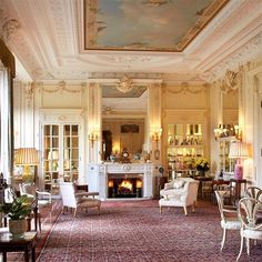 a living room filled with furniture and a fire place under a painting on the ceiling