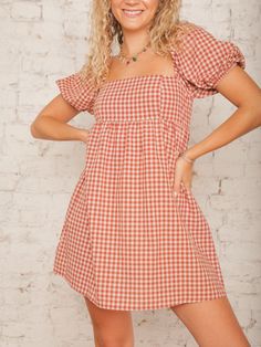 Our Nora Checkered Dress is a sweet babydoll style that brings a playful touch to any outfit with its rust checkered print and square neckline. The short elastic bubble sleeves add a charming detail, perfect for an outdoor fall wedding or event. Style it with ankle booties and a wide-brimmed hat for a cute, carefree look! Details Square Neck Short Elastic Bubble Sleeves Rust Checkered Print Hidden Back Zipper with Hook & Eye Closure Babydoll Style Mini Length Partially Lined Size recs: 2-4 Small, 4-6 Medium, 8-10 Large Provides no stretch Model is 5'8" wearing a size Small Fall Plaid Dress With Square Neck, Gingham Plaid Square Neck Dress For Brunch, Gingham Plaid Dress With Square Neck For Brunch, Casual Plaid Dress With Puff Sleeves, Gingham Puff Sleeve Mini Dress For Picnic, Picnic Gingham Mini Dress With Puff Sleeves, Cute Gingham Square Neck Dress, Casual Gingham Puff Sleeve Dress, Plaid Puff Sleeve Dress For Picnic