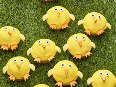 several yellow stuffed birds sitting on top of green grass with eyes and beaks painted on them