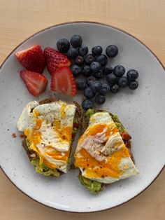 an egg and bacon sandwich with strawberries on the side is ready to be eaten