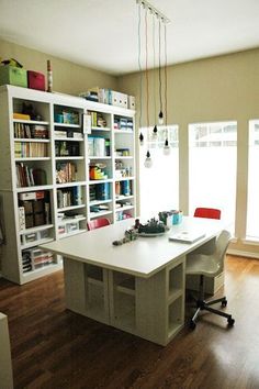 a room with a desk, bookcases and chairs