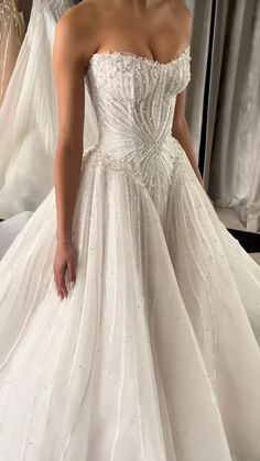 a woman in a white wedding dress standing next to some dresses on mannequins