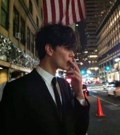 a man talking on a cell phone while standing in front of a building at night