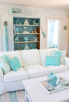 a living room filled with white furniture and lots of blue pillows on top of it