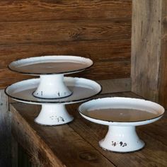 two white dishes with brown liquid on them sitting on a wooden table next to a wood paneled wall