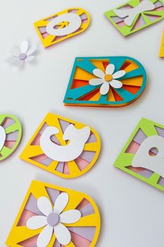 colorful paper cut outs with flowers and shapes on white surface, closeup shot from above