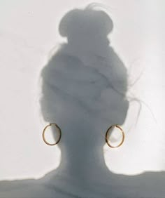 the shadow of a person's head and earring on a white background with shadows