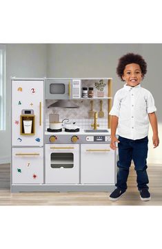 a young boy standing in front of a play kitchen