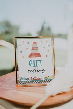 a gift parking sign sitting on top of a wooden table next to a white feather