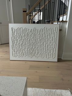 a large white art piece sitting on top of a hard wood floor next to a stair case