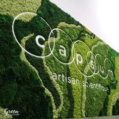 the wall is covered with green plants and white lettering