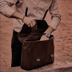 a man holding a brown leather bag on his left hand