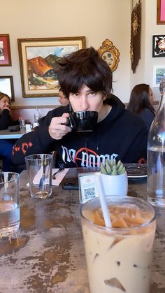 a person sitting at a table drinking from a cup