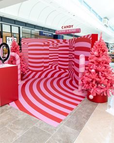 there is a pink and red display in the mall with christmas trees on each side