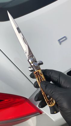 a person in black gloves holding a pair of scissors to the side of a car