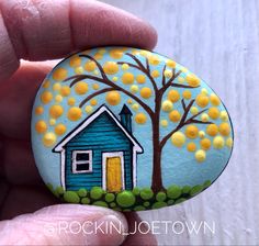 a painted rock with a house and tree on it