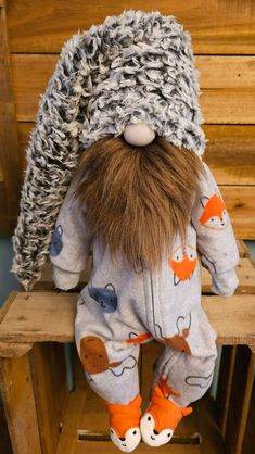 a stuffed animal is sitting on top of a wooden chair with an orange and gray hat