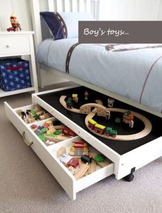 a child's bedroom with toy train tracks and toys in the drawer under the bed