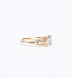 a yellow gold ring with an oval cut diamond and two small round diamonds on the band