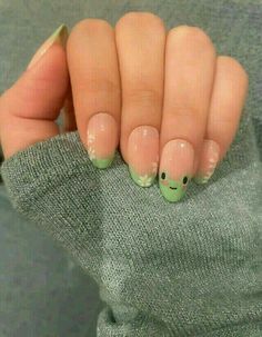 a woman's hand with green and white nail designs on her fingers, holding onto a gray sweater