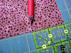 a red pen sitting on top of a piece of fabric next to a ruler and measuring tape