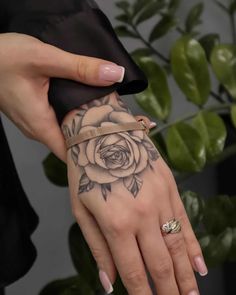 a woman's hand with a rose tattoo on it and a gold band around the wrist