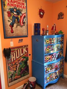 a blue dresser sitting in the corner of a room next to a wall with pictures on it