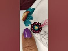 a woman's hand with purple nail polish and flower decorations on her ring finger