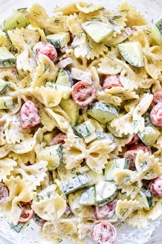 pasta salad with cucumbers and tomatoes in a glass bowl