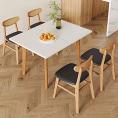 a white table with four chairs and a bowl of oranges on the dining room table