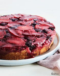 a blueberry cheesecake on a white plate with a pink napkin next to it