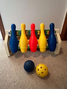 three plastic bowling balls sitting in front of a row of toy bowling pins on the floor