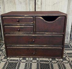 an old wooden dresser with two drawers on the bottom and one drawer open, sitting on a rug