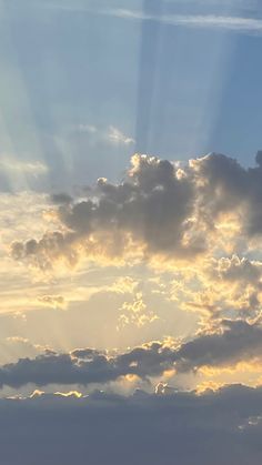 an airplane flying in the sky with sunbeams and clouds behind it at sunset