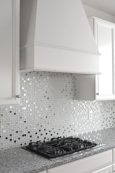 a stove top oven sitting inside of a kitchen next to white cabinets and counter tops