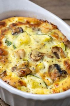 a casserole dish with mushrooms, cheese and broccoli in it on a wooden table