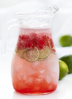 a pitcher filled with watermelon and limes on top of a white table