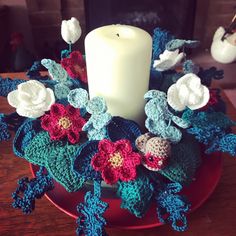 a crocheted wreath with flowers and a candle